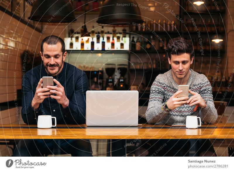 Freunde, die Handy und Laptop benutzen. Mann Kaffee Freundschaft Jugendliche Teamwork Menschengruppe Lifestyle PDA Mobile Mitteilung benutzend Text Computer