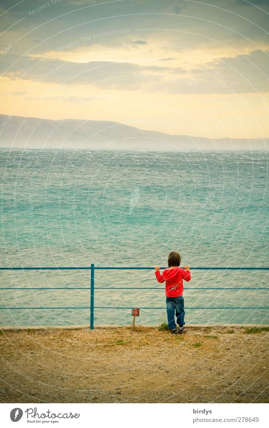 Kind steht an einem Gelländer und schaut auf das kroatische Mittelmeeer hinaus wo gerade die Bora über das Wasser peitscht Ferne Sommerurlaub Meer Insel 1