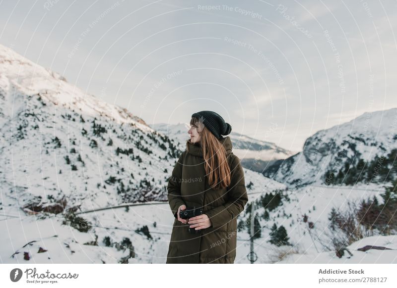 Junge Frau in Skijacke mit Kamera zwischen den Bergen Fotokamera Berge u. Gebirge Pyrenäen Dame Hut Schnee Hügel wunderbar Jugendliche kalt anhaben Wärme Stoff