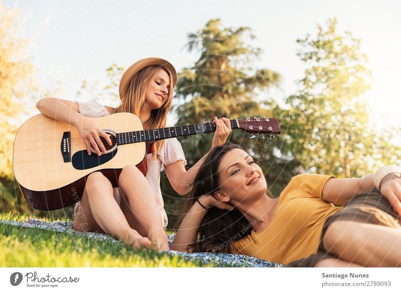 Schöne Frauen, die Spaß am Gitarrespielen im Park haben. Picknick Freundschaft Jugendliche Glück Gitarrenspieler Sommer Mensch Freude Spielen Musik Erwachsene