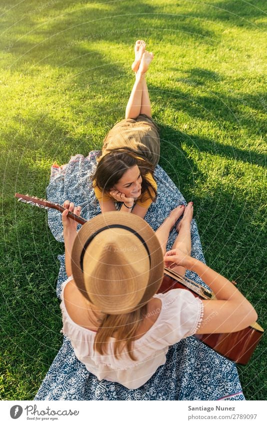 Schöne Frauen, die Spaß am Gitarrespielen im Park haben. Picknick Freundschaft Jugendliche Glück Gitarrenspieler Sommer Mensch Freude Spielen Musik Erwachsene