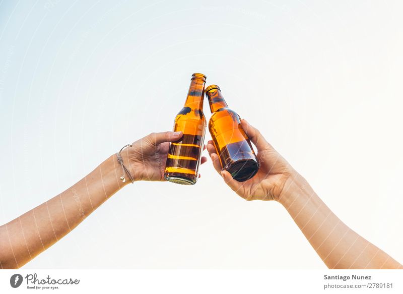 Weibliche Freunde jubeln, wenn klirrende Bierflaschen in den Händen liegen. Paar Toastbrot heiter Zuprosten Glas Flasche Hand Frau Glück Hintergrundbild