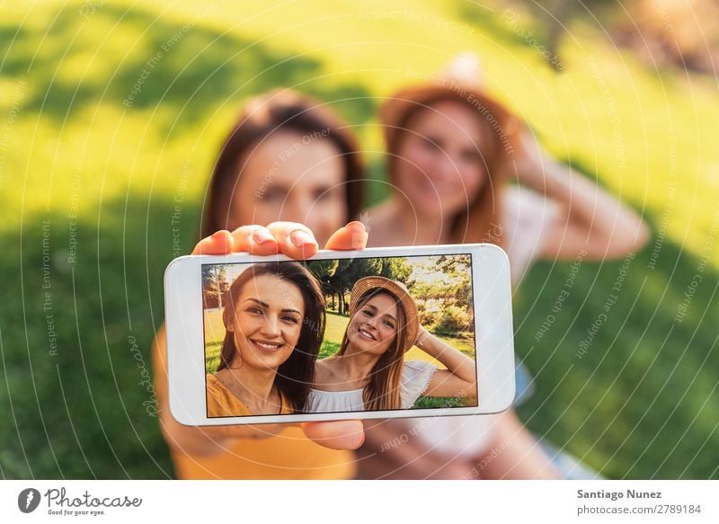 Wunderschöne Frauen, die im Park ein Selbstporträt machen. Picknick Freundschaft Jugendliche Glück Sommer Mensch Freude Mobile PDA Telefon Solarzelle Fotografie