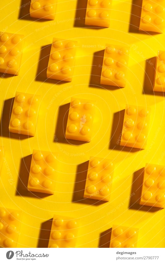 Gelbe, einfarbige geometrische Kunststoffwürfel. Bauspielzeug Design Spielen Kind Kindheit Spielzeug Backstein bauen gelb Farbe Blöcke Hintergrund Reihen