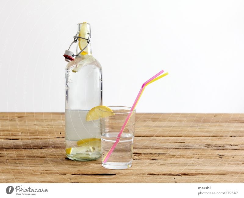 Zitronenlimonade Getränk trinken Erfrischungsgetränk Limonade Flasche Glas gelb Frucht fruchtig Halm Durstlöscher Wasser Holztisch Farbfoto Innenaufnahme