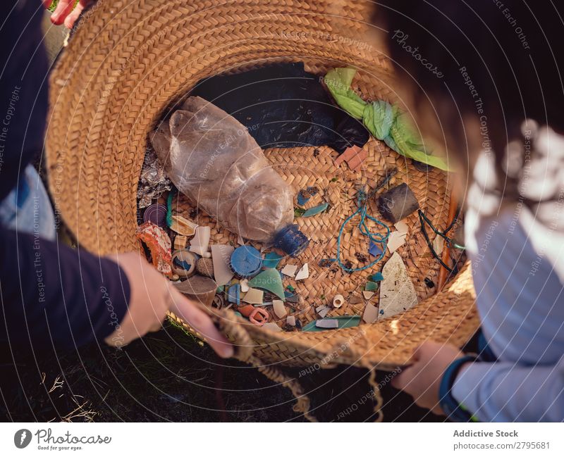 Person und Kinder mit Müllhaufen in den Händen in der Nähe des Korbes Müllbehälter Haufen Hand Mensch Anhäufung Container Kunststoff Aufräumen Jugendliche