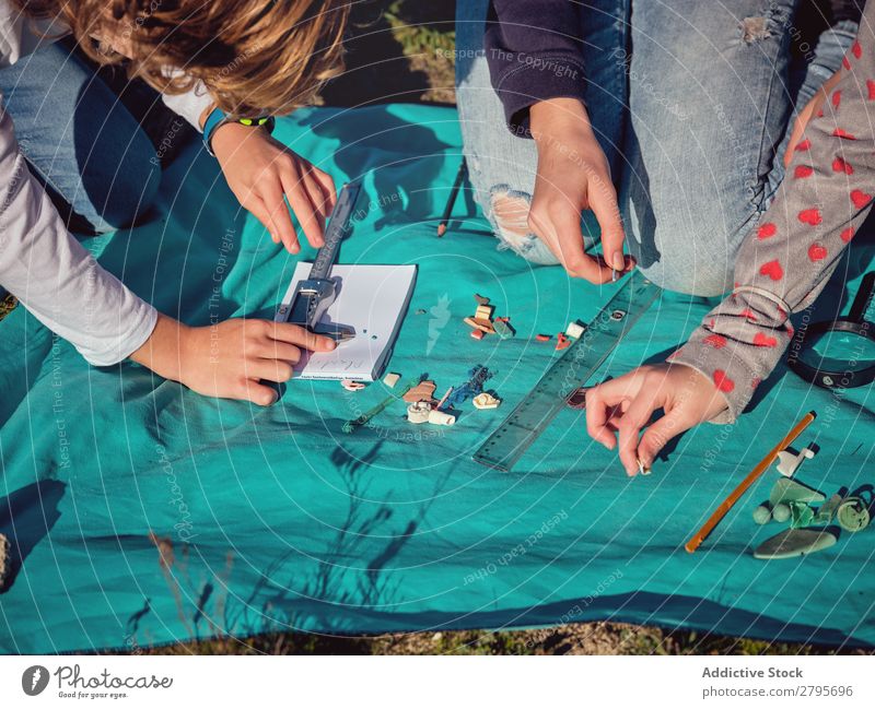 Leute, die kleine Dinge auf Papier auf der Decke messen. Mensch messend Bettdecke Kunststoff Hand Messschieber Boden Umwelt Messung Müllbehälter Aufräumen