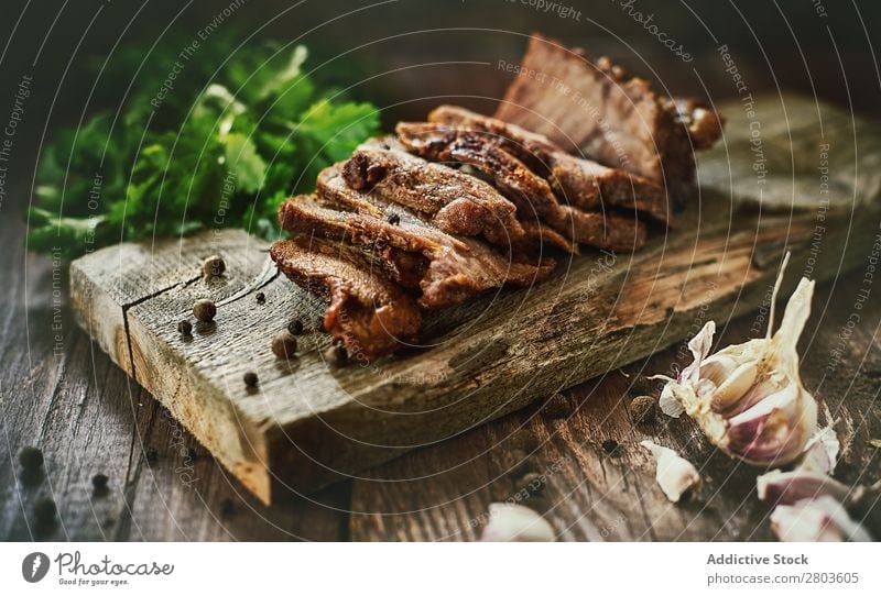 Gewürze in der Nähe von leckerem gebratenem Fleisch Schinken Knoblauch Petersilie Tisch Holzplatte Kräuter & Gewürze Lebensmittel Scheiben Abendessen frisch