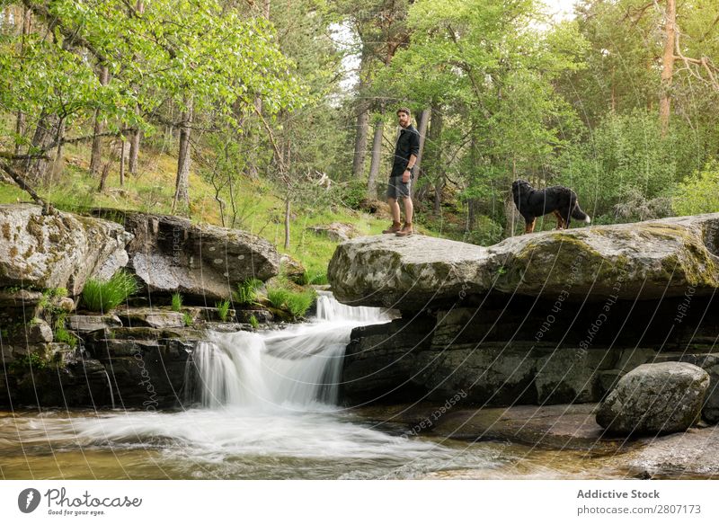 Junger Mann ruht sich nach dem Abenteuer mit seinem Hund am Wasserfall aus. Natur Sommer Ferien & Urlaub & Reisen genießend Gesundheit Körper Entwurf grün