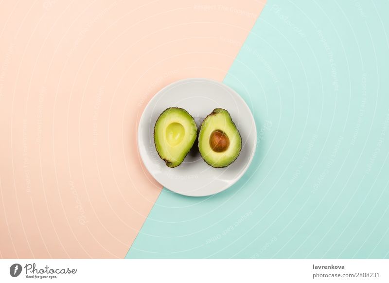 Avocado auf weißem Teller auf pastellfarbenem Hintergrund schneiden Scheibe natürlich roh frisch grün geschnitten reif organisch Ernährung