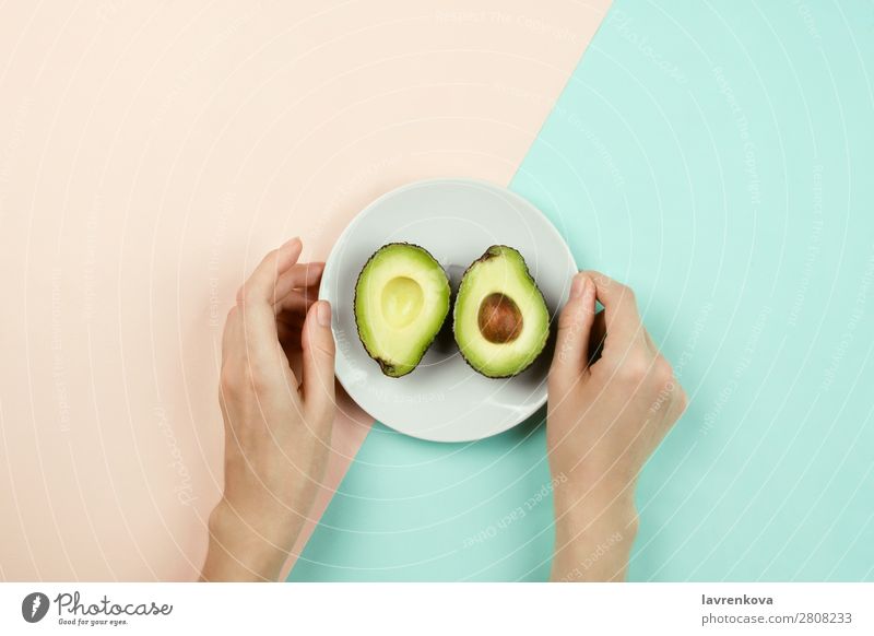 Avocado auf weißem Teller und Frauenhänden schneiden. Vegetarische Ernährung Vegane Ernährung Frucht Essen flache Verlegung Zutaten Diät Gesundheit