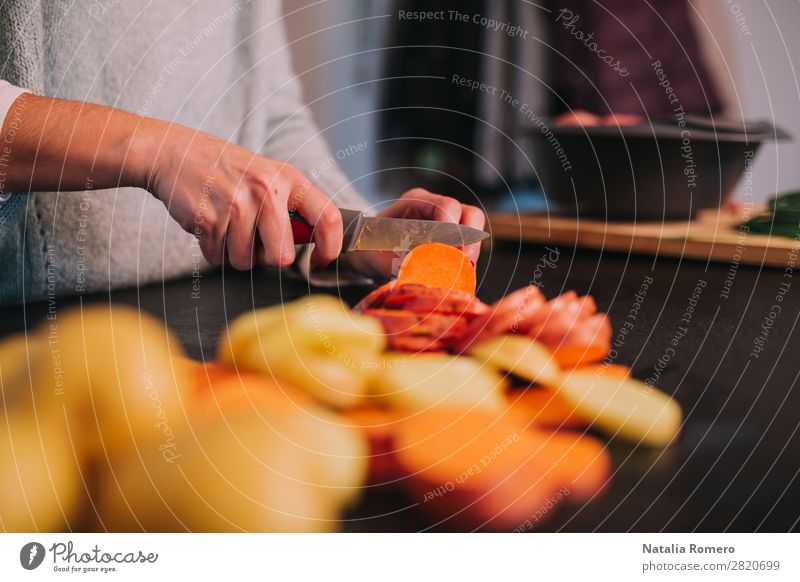 eine Person, die Kartoffeln und Süßkartoffeln in einer schönen Küche schneidet. Gemüse Essen Mittagessen Abendessen Diät Tisch Mensch Frau Erwachsene Hand Natur