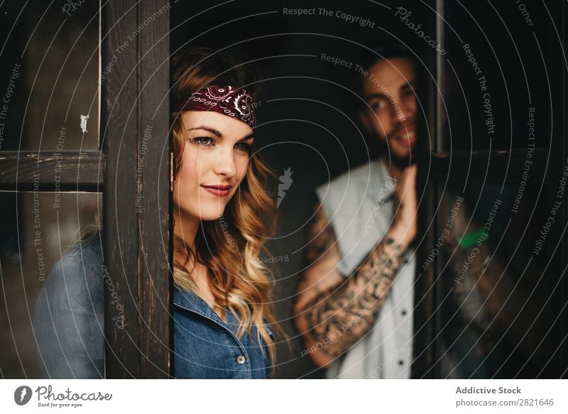 Lächelnde Frau mit Band auf dem Kopf gegen ihren Freund, der sie ansieht. Paar Tattoo Porträt Fenster Wegsehen hübsch schön attraktiv Blick Romantik