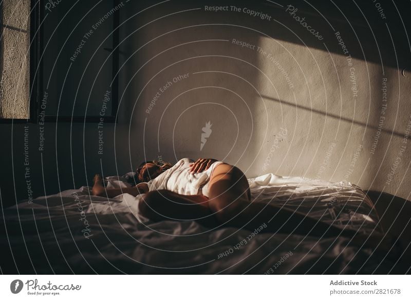 Sinnliche Frau, die im Sonnenlicht auf dem Bett liegt. lügen schlafen Textfreiraum Hintergrundbild itim Intimität Wand Haut Bräune unkenntlich genießen Erotik