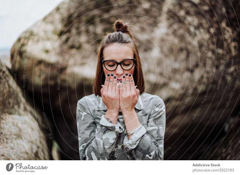 Frau in Gläsern betend auf Steine Stil Natur Felsen stehen Augen geschlossen Brillenträger attraktiv schön Jugendliche Mode Schickimicki hübsch Coolness