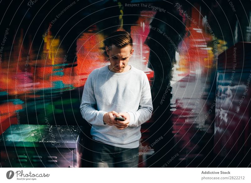 Lässiger Mann auf der Straße, der das Smartphone durchsucht. Graffiti Stadt Großstadt London England Stil Stadtzentrum modern Hand-in-Tasche Kunst Fürsorge