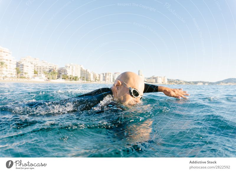 Mann im Neoprenanzug schwimmend im Meer Schwimmsport Sport Athlet Wassersport Bewegung Aktion Ferien & Urlaub & Reisen Rudern Freizeit & Hobby Sonnenlicht