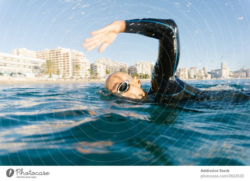 Mann im Neoprenanzug schwimmend im Meer Schwimmsport Sport Athlet Wassersport Bewegung Aktion Ferien & Urlaub & Reisen Rudern Freizeit & Hobby Sonnenlicht