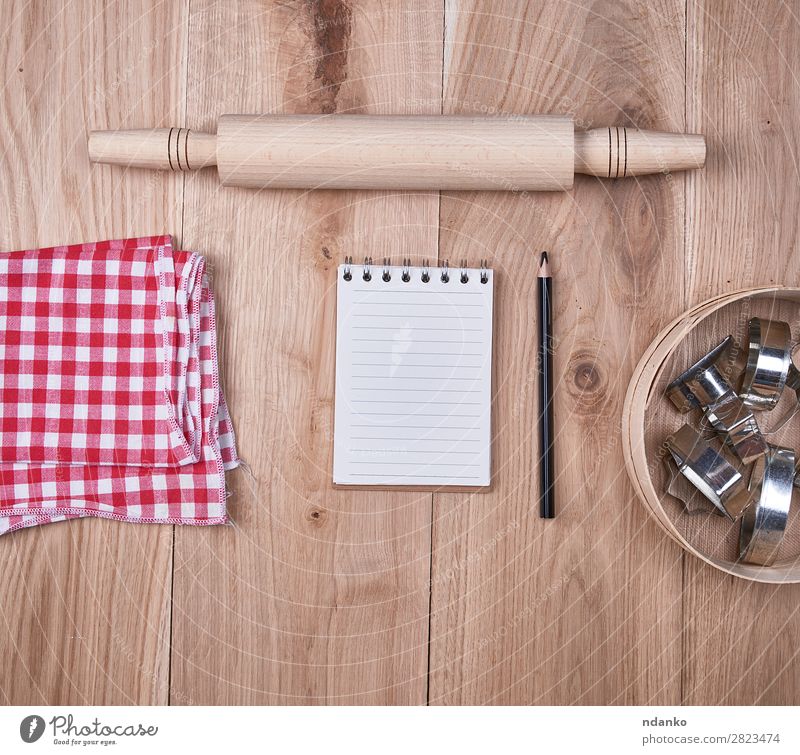 offenes Notizbuch in einer Zelle, rundes Holzsieb Besteck Tisch Küche Sieb Papier oben braun gelb rot Hintergrund blanko Essen zubereiten Textfreiraum leer