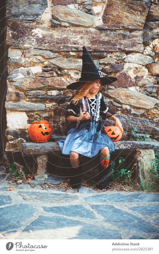 Kleines Mädchen in Hexenkostüm auf der Bank sitzend Halloween Süßwaren Essen Hundefutter Ferien & Urlaub & Reisen Entertainment Festspiele Jahreszeiten Kostüm