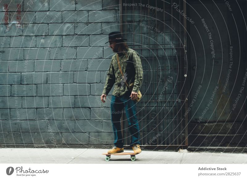 Mann fährt Skateboard in der Stadt Reiten Straße stehen Textfreiraum Coolness selbstbewußt Hut bärtig ernst brutal Vollbart Mensch Großstadt Schickimicki