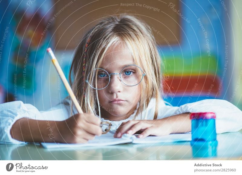 Nachdenkliches Mädchen beim Schreiben im Unterricht Klassenraum sitzen Schreibtisch schreibend Bleistift Zeichnung Denken Fürsorge gelangweilt niedlich Bildung