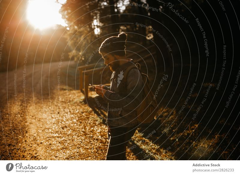 Ein Mann, der ein Handy im Wald benutzt. Tourist Porträt Texten Rucksack Telefon Straße Technik & Technologie Herbst Tourismus Ferien & Urlaub & Reisen