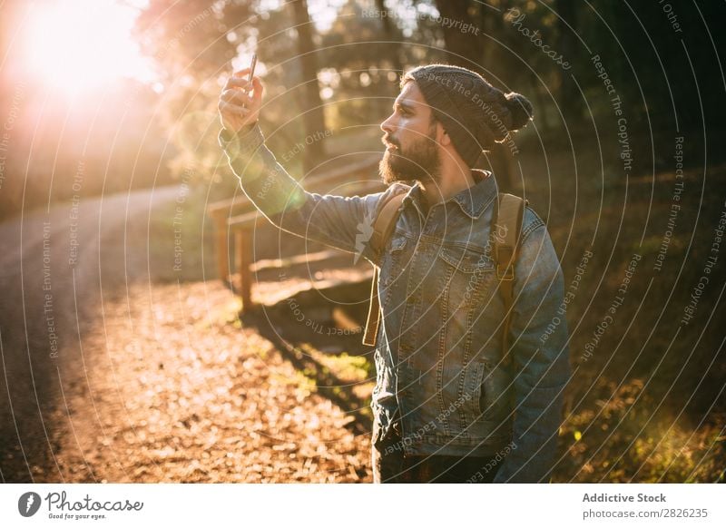 Mann mit Selfie auf sonniger Herbststraße Tourist Wald Porträt Rucksack Telefon Straße Technik & Technologie Tourismus Ferien & Urlaub & Reisen Abenteuer
