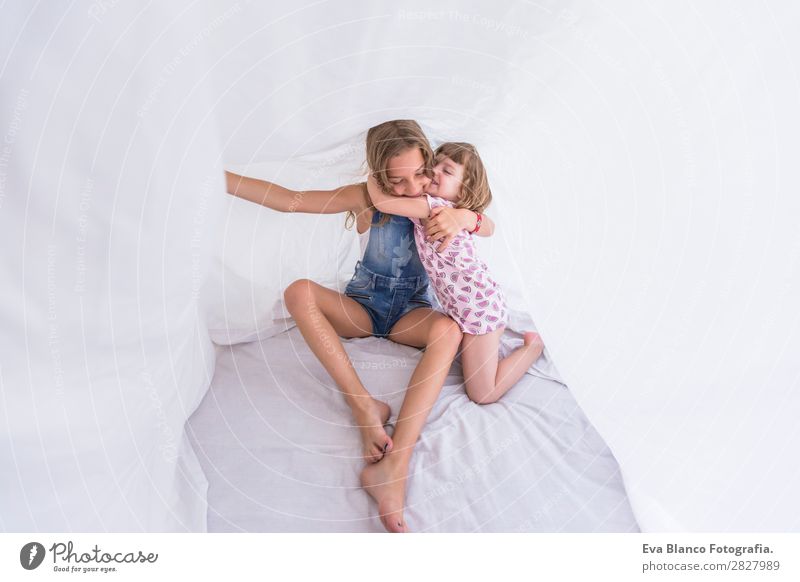 Zwei schöne Schwesternkinder, die unter weißen Laken spielen. Lifestyle Freude Glück Freizeit & Hobby Spielen lesen Sommer Schlafzimmer Kind Mensch feminin Baby