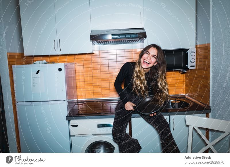 Frau auf Küchentisch mit Pfanne sitzend hübsch Körperhaltung heimwärts Tisch Blick in die Kamera schön Lifestyle Jugendliche Mensch Glück attraktiv Porträt