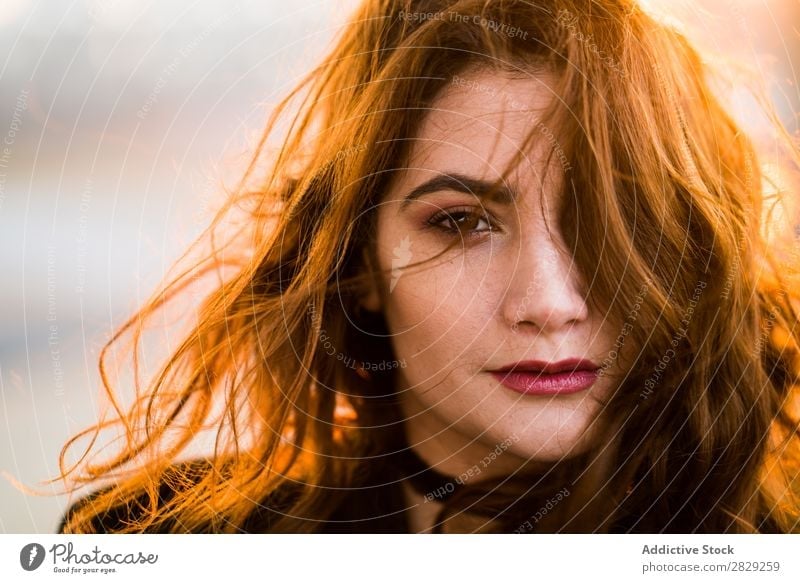 Porträt einer ernsthaften jungen Frau, die mit fliegenden Haaren in die Kamera schaut. Sonnenuntergang Behaarung selbstbewusst in die Kamera schauen lässig