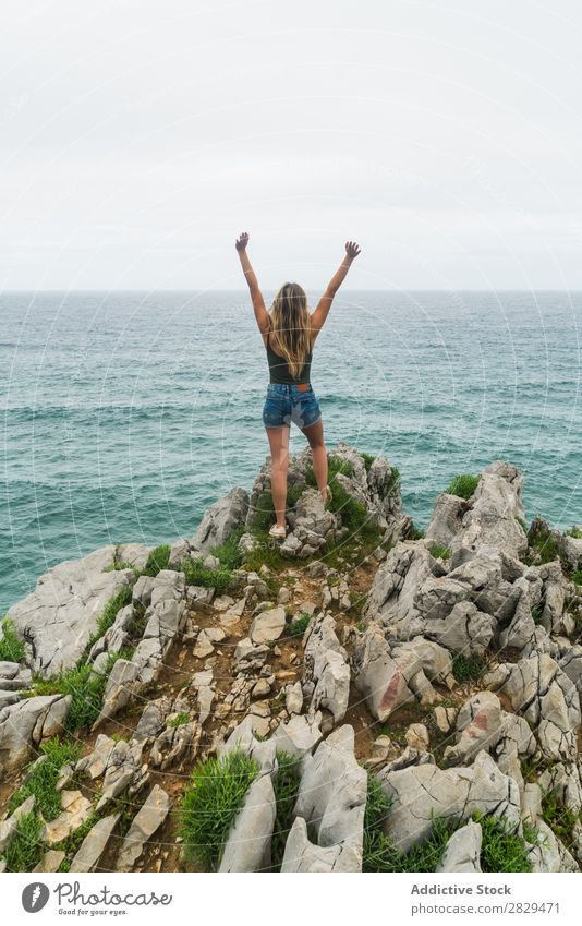 Mädchen mit erhobenen Armen, stehend auf der Klippe. Frau Meer schön Felsen Sommer Natur Ferien & Urlaub & Reisen Wasser Landschaft Jugendliche blau Lifestyle