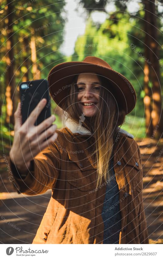 Lächelnde Frau nimmt Selfie im Wald. Tourist grün Natur Umwelt heiter Glück PDA nehmen Schuss Hut hübsch natürlich Jahreszeiten Pflanze Blatt Licht frisch hell