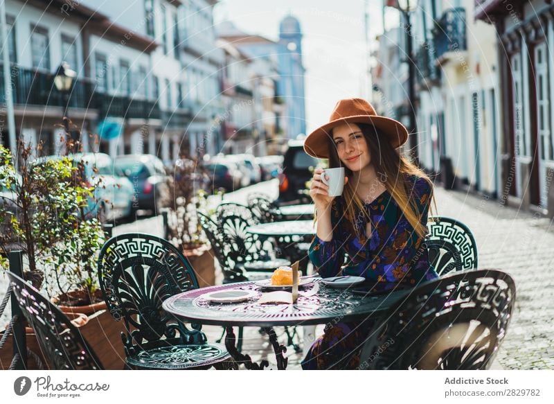 Lächelnde Frau mit Tasse im Außencafé hübsch Stil Straße Hut Kaffee Café Außenaufnahme Mode schön Jugendliche Porträt attraktiv Großstadt Lifestyle Model