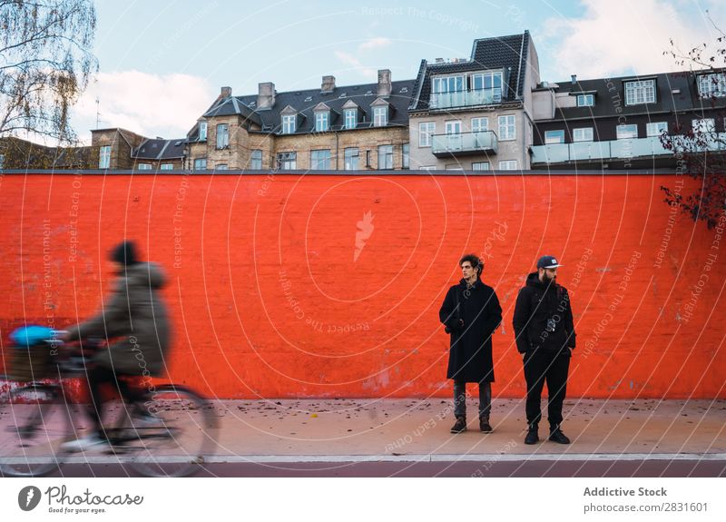 Zwei Männer an der orangefarbenen Wand Mann stehen Orange Zusammensein Straße gutaussehend Großstadt Jugendliche Stadt Lifestyle lässig Mode Stil Erwachsene