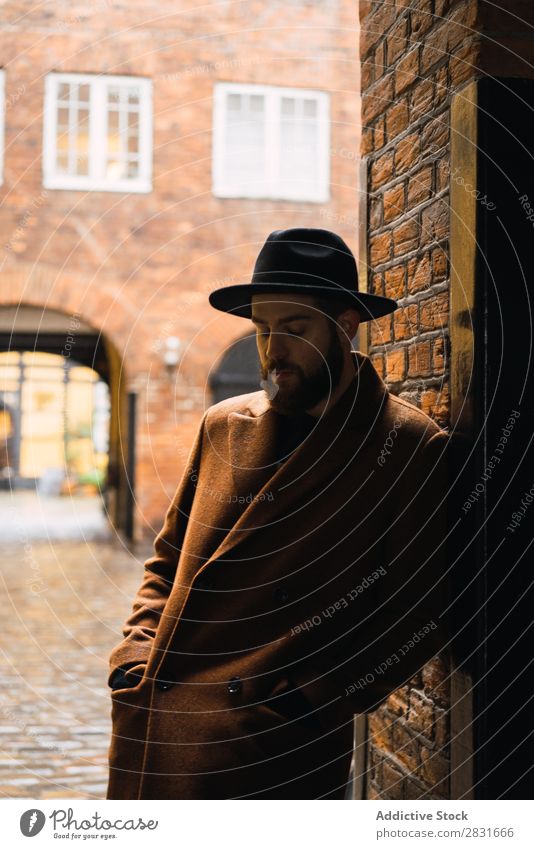 Stilvoller Mann, der sich an die Wand lehnt. gutaussehend Großstadt Mantel Hut anlehnen Straße Jugendliche Stadt Lifestyle lässig Mode Erwachsene modern Mensch