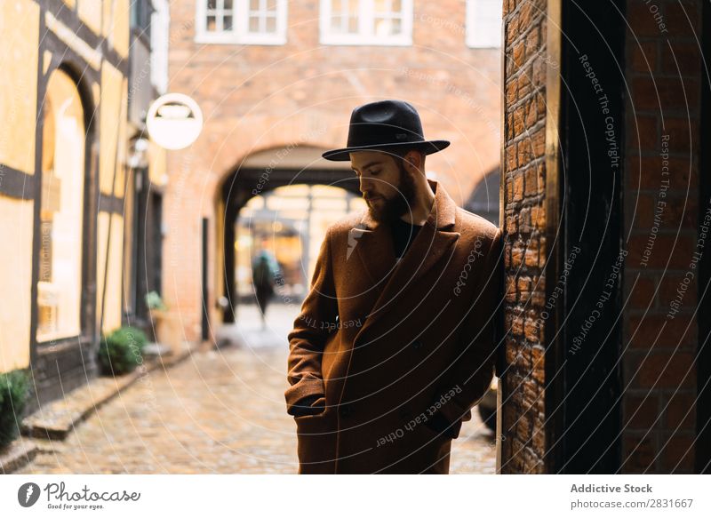 Stilvoller Mann, der sich an die Wand lehnt. gutaussehend Großstadt Mantel Hut anlehnen Straße Jugendliche Stadt Lifestyle lässig Mode Erwachsene modern Mensch