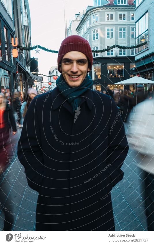 Fröhlicher Mann auf überfüllter Straße Lächeln stehen heiter Porträt Blick in die Kamera warme Kleidung gutaussehend Großstadt Jugendliche Stadt Lifestyle