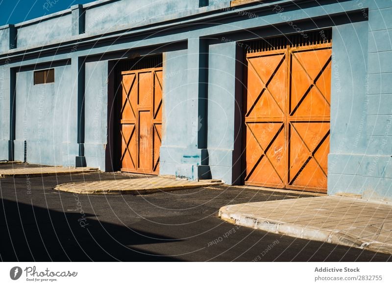 Orangefarbene Tore in blauer Wand Außenseite Metall Gebäude Konsistenz mehrfarbig Hauseingang Farbe hell Tag Architektur Stahl Tür Fassade Strukturen & Formen