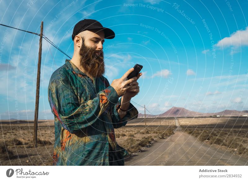 Mann mit Telefon auf der Landstraße Tourist Berge u. Gebirge Wolken Feld PDA benutzend Browsen bärtig Natur Landschaft natürlich Felsen Stein Lanzarote Spanien
