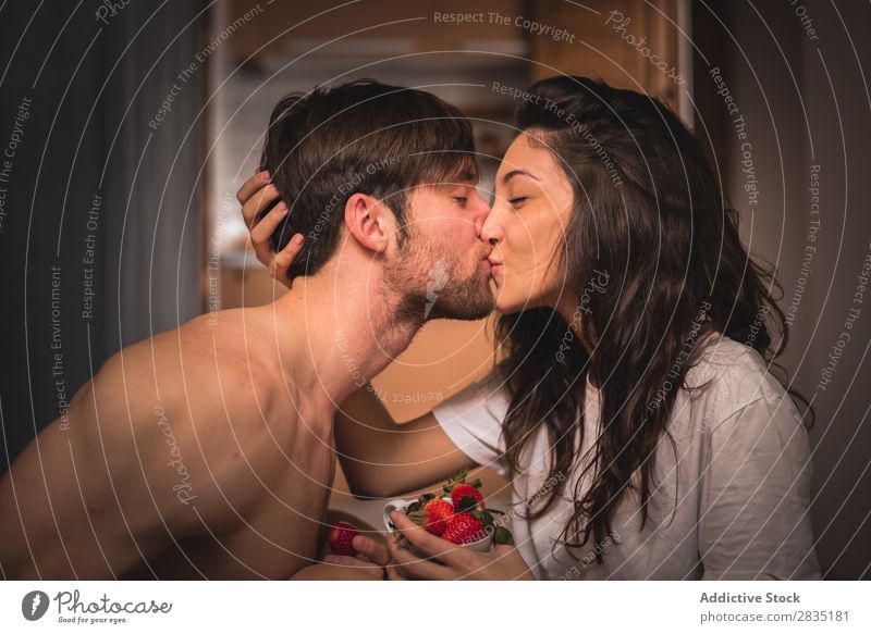 Ein Paar küsst sich mit Erdbeeren. Jugendliche Küssen Frau Mann Liebe Partnerschaft Augen geschlossen Beeren rot saftig Frucht Mensch 2 Romantik Zusammensein