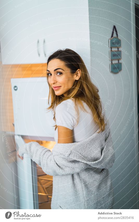 Hübsche Frau am geöffneten Kühlschrank hübsch heimwärts Jugendliche nehmen Öffnung Körperhaltung Porträt schön Lifestyle Beautyfotografie attraktiv Dame Raum