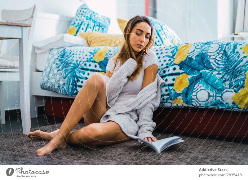Hübsche Frau liest ein Buch auf dem Boden. hübsch heimwärts Jugendliche Körperhaltung sitzen lesen Bett Roman Literatur Porträt schön Lifestyle Beautyfotografie