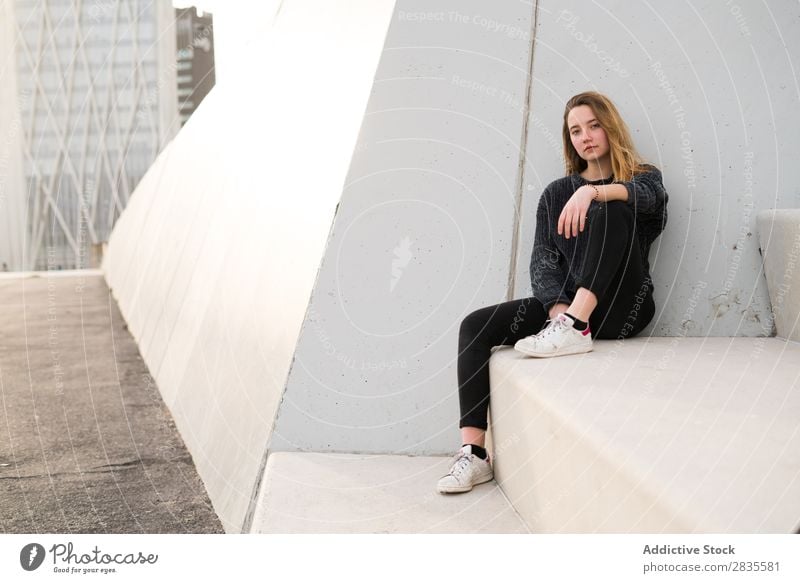 Frau auf Betonblock sitzend Block Treppe Gebäude träumen Fürsorge besinnlich Blick in die Kamera hübsch Jugendliche schön Pullover Großstadt Stadt Straße lässig