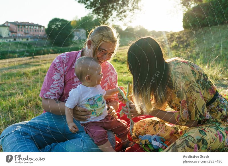 Glückliche Familie im Park Mutter Kind Rasen grün Sonnenstrahlen Mensch Frau Fröhlichkeit Sommer Lifestyle Liebe gleichgeschlechtliche Eltern Homosexualität