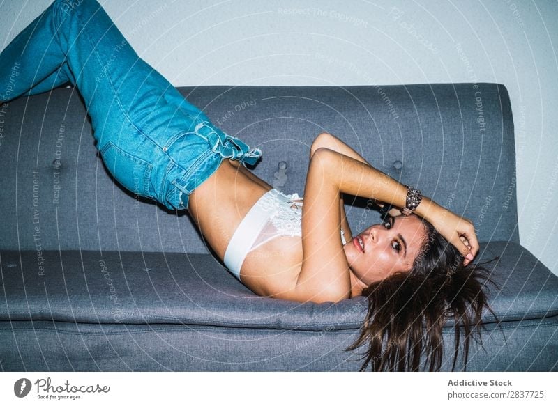 Junge provokante Frau auf dem Sofa verführerisch Körperhaltung aufreizend Versuchung Unterwäsche BH Stil Model selbstbewußt brünett sexuell genießen Bekleidung
