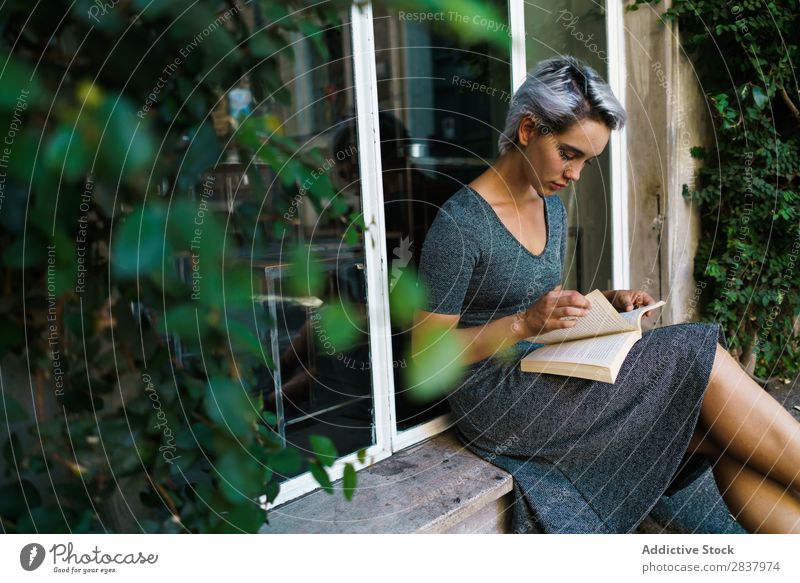 Frau liest Buch am Fenster Straße sitzen Fenstersims schön Mädchen Jugendliche Schüler hübsch Erwachsene Lächeln Großstadt Beautyfotografie attraktiv lässig