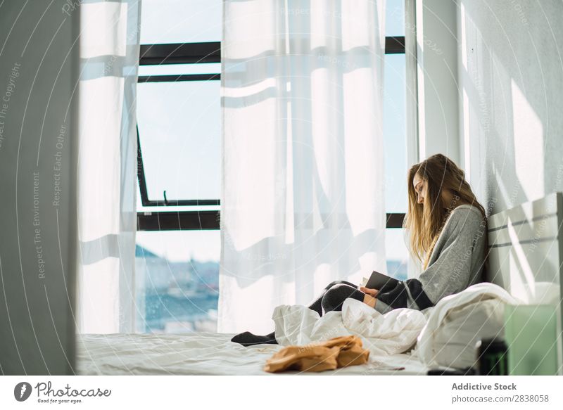 Mädchen kühlend mit Buch in gemütlichem Bett Frau lesen Morgen konzentriert Gelassenheit Sonnenlicht friedlich blond Geborgenheit heimwärts Raum aussruhen