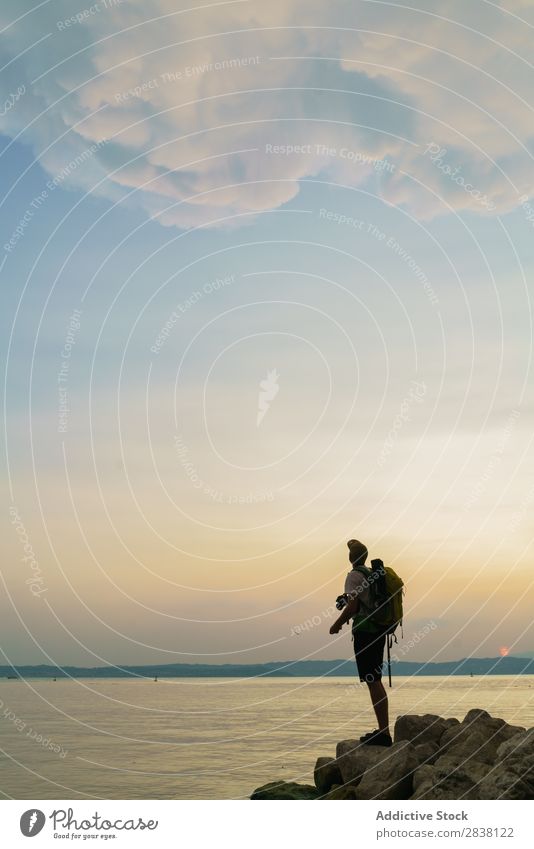 Backpacker, der auf Felsen posiert. Mann Reisender Körperhaltung Aktion Sommer Jugendliche Abenteuer Meer Landschaft Großstadt so tun, als ob lustig Sport