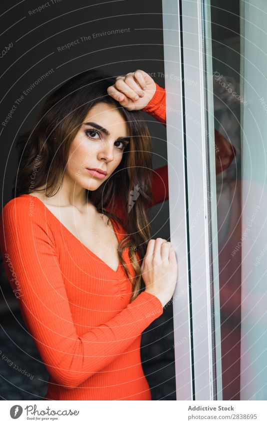 Hübsche Frau, die sich an das Fenster lehnt. heimwärts hübsch anlehnen Blick in die Kamera Orange Kleid Jugendliche Körperhaltung Erholung Porträt schön